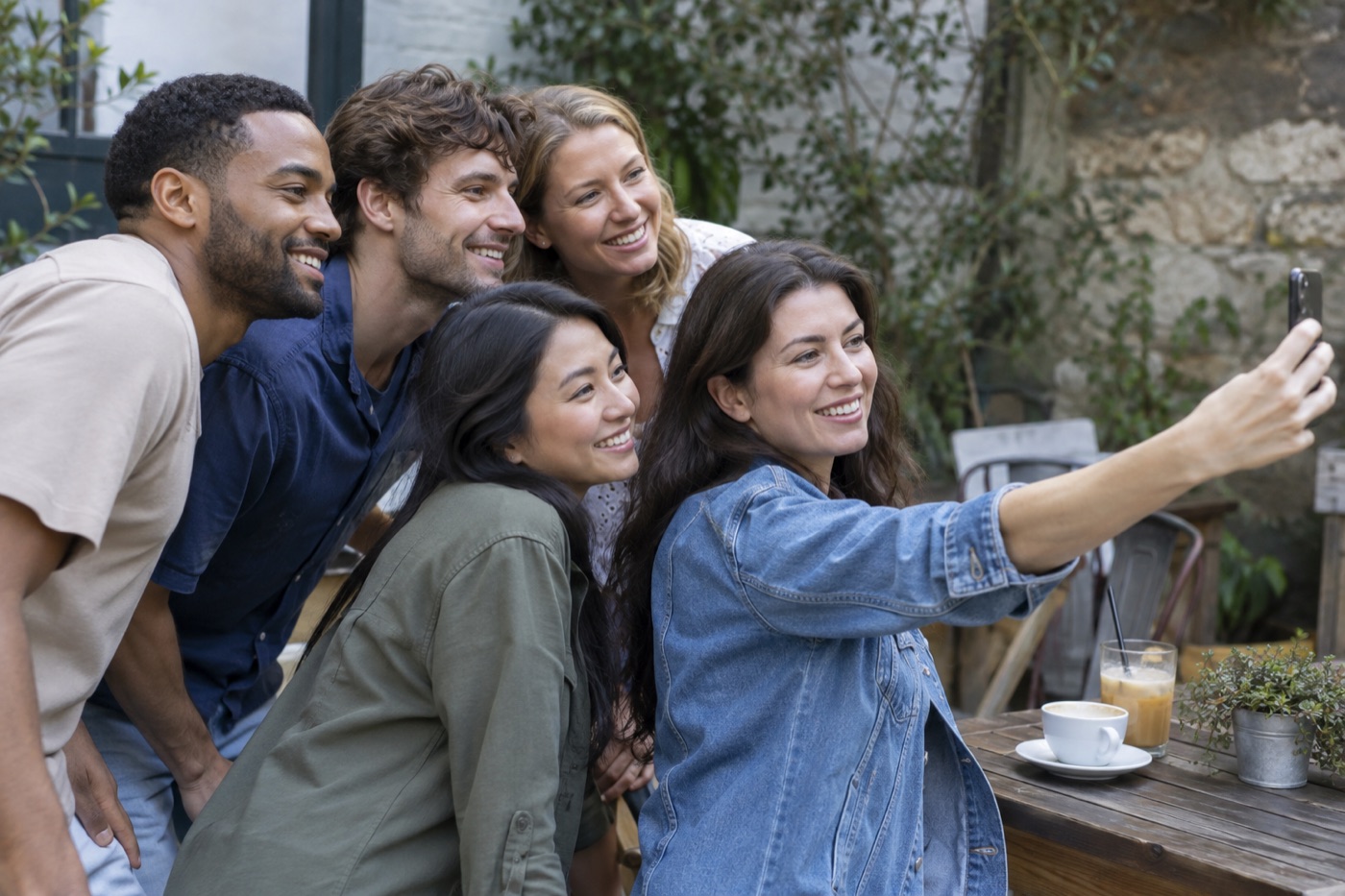 Five friends stagger their positions while checking a group selfie frame
